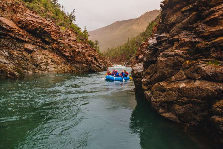 White water rafting group paddling down calm section of river